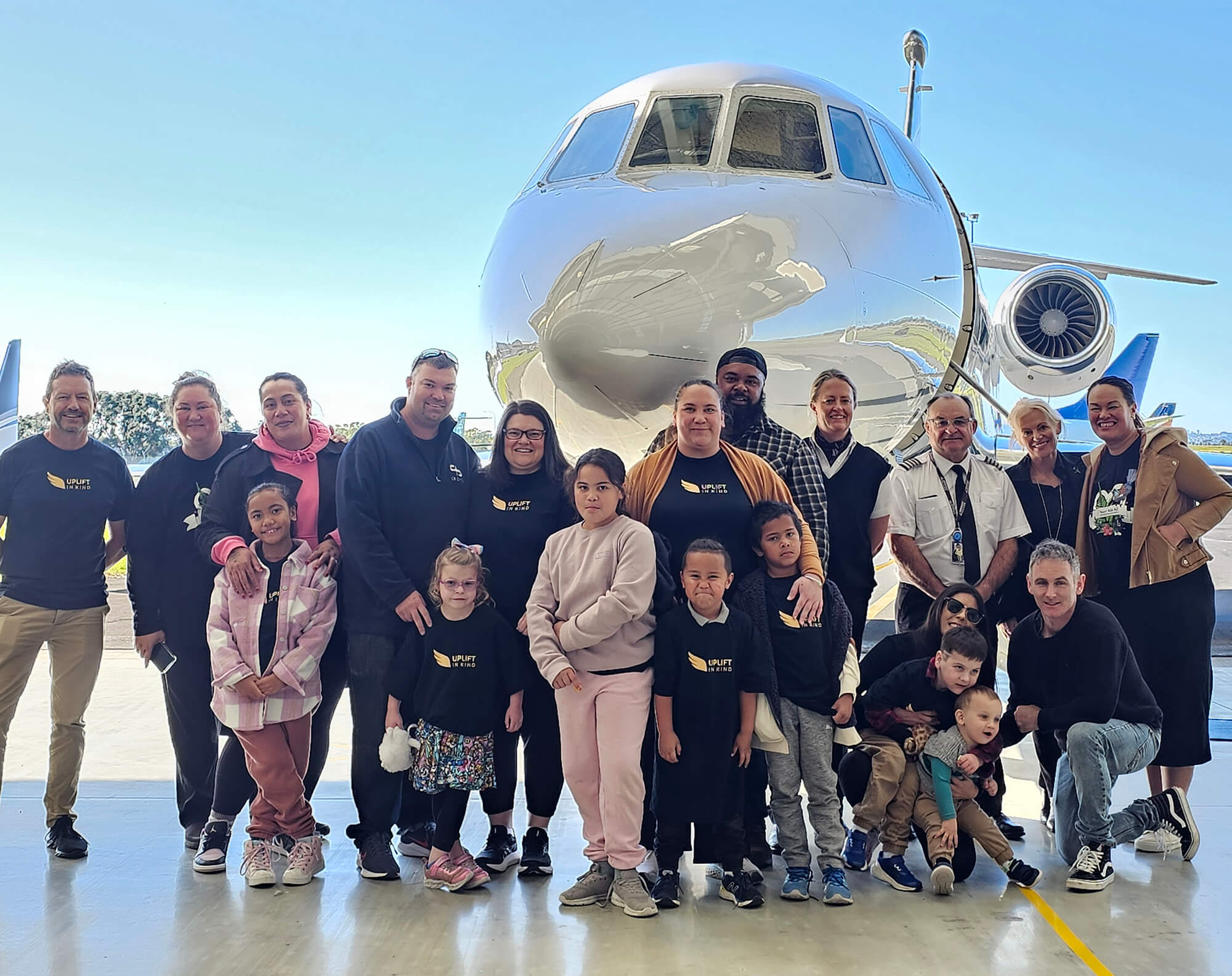 Uplift in Kind families and DJets crew gathered in front of a private jet in the Auckland hangar